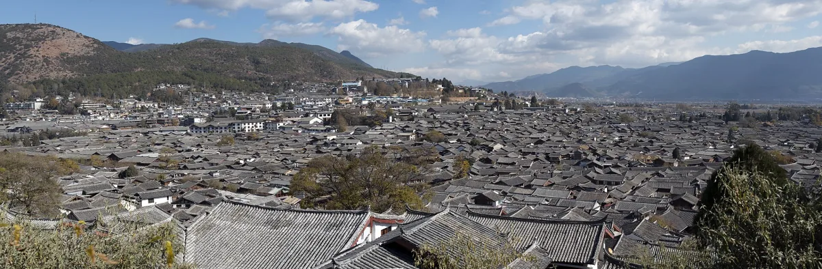 Lijiang's traditional tiled rooftops and surrounding mountain landscape in Yunnan
